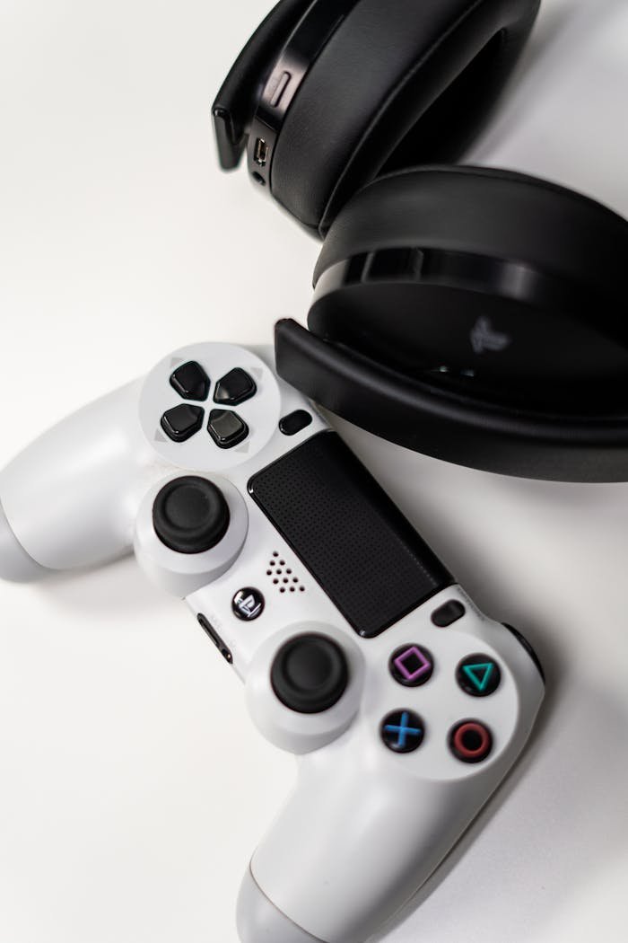 A top view of a white game controller paired with black headphones on a white background.